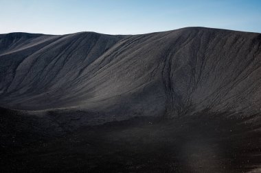 Arka plan olarak koyu kum, siyah volkanik kum dalgaları dokusu, havadan yakın çekim. Doğa örüntüsü kavramı.