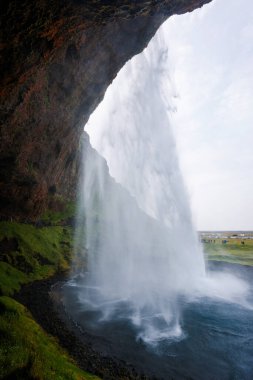 Seljalandsfoss, İzlanda 'da ünlü ve benzersiz bir şelale ziyaretçileri şelalenin arkasında küçük bir mağaraya yürüyor. Trip konsepti.