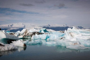Yazın Jokulsarlon Buzul Gölü, eriyen buzdağları, muhteşem buzullar, ve arka planda gökyüzü, hava manzarası
