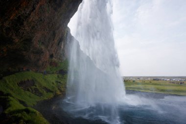 Seljalandsfoss, İzlanda 'da ünlü ve benzersiz bir şelale ziyaretçileri şelalenin arkasında küçük bir mağaraya yürüyor. Trip konsepti.