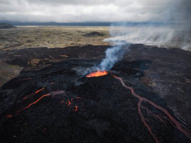 İzlanda 'da aktif bir volkan patlamasının muhteşem manzarası. Volkanik bir çatlak, bir vadiye akan lav akımını serbest bırakıyor..