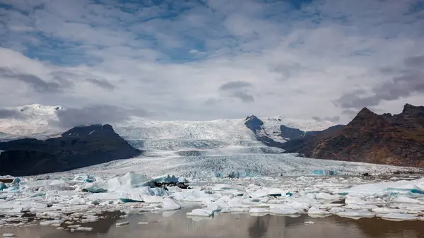 Jokulsarlon glacier lagoon in summer, with melted icebergs, spectacular glacial tongue, and sky in the background, aerial view