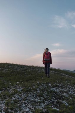 Sırt çantalı bir kadın yürüyüşçü silueti yukarı doğru yürüyor ve gün batımında gökyüzünün tadını çıkarıyor. İlham ve sağlıklı yaşam tarzı kavramları.