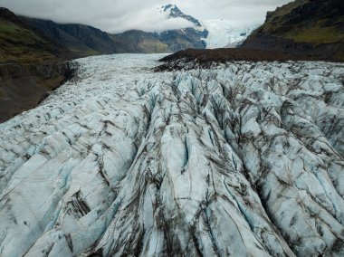 İzlanda 'da bulutlu bir günde Svinafellsjokull buzulu, dağlarla çevrili eşsiz buz oluşumları, ve bir buzul gölü, hava manzarası. Doğa ve küresel ısınma kavramları.