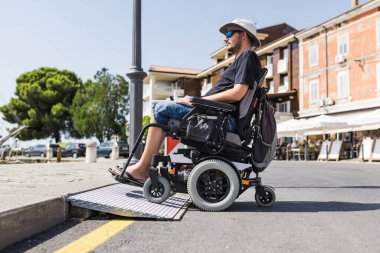 Tekerlekli sandalyedeki erkek turist deniz kenarındaki rampadan geçiyor. Engelli ve ulaşılabilir turizm kavramları.