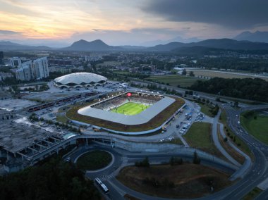 Slovenya 'nın başkenti Ljubljana' daki modern spor parkı kompleksi ve günbatımında manzaralı dağ manzarası, hava manzarası.