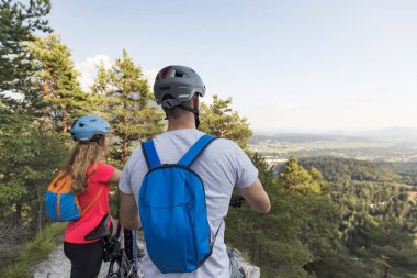 İki turist elektrikli dağ bisikletleriyle güzel bir dağ manzarasının tadını çıkarıyorlar.