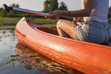 Rahat bir kano gezisi, güzel bir yaz günü gölde kano süren bir kadın. Doğa aşığı ve aktif yaşam kavramları.