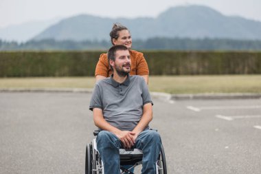 Özürlü bir adamın tekerlekli sandalyesini dışarı itmesine yardım eden kişisel asistanım. Yardım hizmeti kavramı.