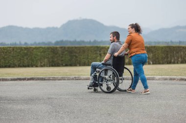 Özürlü bir adamın tekerlekli sandalyesini dışarı itmesine yardım eden kişisel asistanım. Yardım hizmeti kavramı.