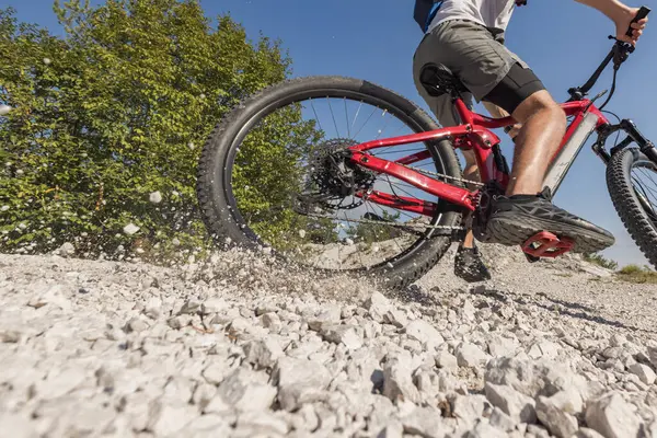 stock image Recreational cyclist riding an electric mountain bike on white gravel path. EMTB cycling concept.