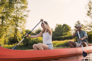 Sıcak bir yaz öğleden sonrasını gölde geçiren çift, sakin suda kano çırpıyor. Kano ve sağlıklı yaşam tarzı kavramları.