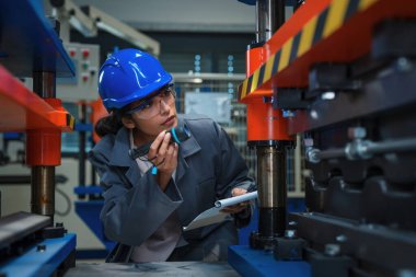 Endüstri fabrikasında bakım ve güvenlik için ağır makineleri kontrol eden kadın mühendis..