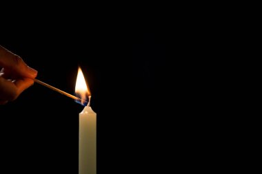 Erkek el şimşeği siyah arka planda beyaz bir mum, yakın çekim. Hafıza, sembol, din ve dua kavramları.