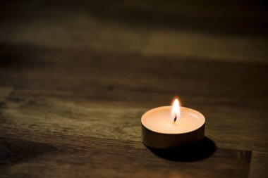 Tahta masadaki küçük beyaz çay mumu, yakın çekim. Tealight ambians konsepti.
