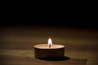 Tahta masadaki küçük beyaz çay mumu, yakın çekim. Tealight ambians konsepti.