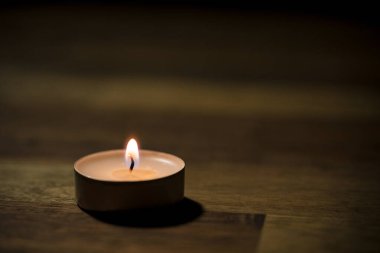 Tahta masadaki küçük beyaz çay mumu, yakın çekim. Tealight ambians konsepti.