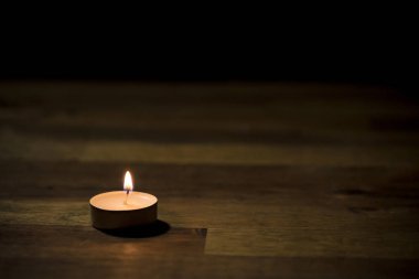 Tahta masadaki küçük beyaz çay mumu, yakın çekim. Tealight ambians konsepti.
