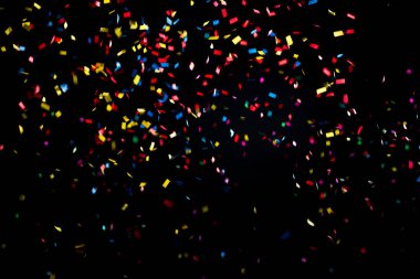 Colorful and multiform glitter confetti explosion on a black background, studio shot. Moment of happiness and festivity concept. clipart