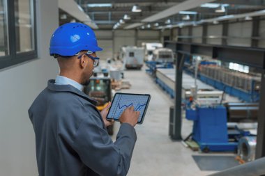 Fabrika makine üretimi ve iş prosedürü, dikiz görüntülerini kontrol etmek için tablet ve grafik verileri kullanan genç mühendis. Sektör kariyer kavramı.