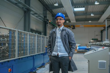 African American engineer with a blue helmet and safety goggles, operating a control panel, controlling and automating industrial processes. clipart