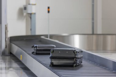 Bir havaalanında bagaj teslim, varış bölgesinde iki bavul taşıma bandı. Seyahat, ulaşım ve bagaj atlıkarınca kavramları.