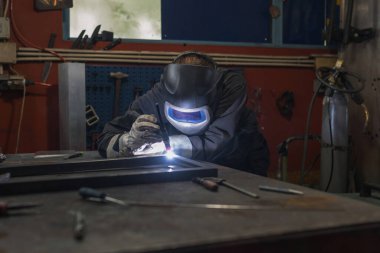 Kaynakçı, metal parçaları düzgün bir açıyla kaynaklama konusunda yetenekli ve hassas. Sanatçılık ve metal işçiliği kavramları.