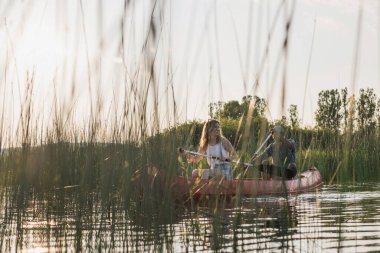 Mutlu çift, gölde kano gezintisinin tadını çıkartıyor. Etrafı güzel yeşil doğa ile çevrili, dinleniyorlar. Kano gezisi kavramları.