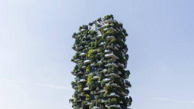 Konut kulesi, çeşitli bitkiler ve ağaçlarla kaplı balkonları olan modern mimarinin bir örneği. Sürdürülebilirlik ve ağaç gökdelen kavramı.