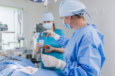 Klinikteki bir ameliyathanede iki veteriner, bir veteriner ve bir teknisyen..