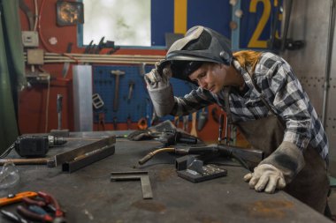 Teçhizatlı kadın atölyede kaskını çıkarıyor..