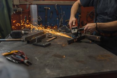 Kaynakçı öğütücüyle metal bir boruyu işliyor, kıvılcım çıkarıyor. Metal işleri, kaynakçılık ve elle tutulur kavramlar.