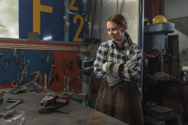 Bir atölyede öğütücüyle çalışan kadın kaynakçının portresi..