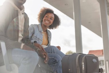 Gülümseyen yolcular, tren istasyonuna ulaşmayı bekleyen bir çift yaklaşan yolculukları için heyecanlı..