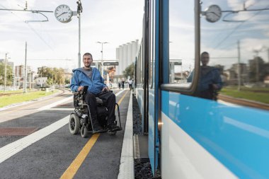 Elektrikli sandalyede engelli bir adam trene biniyor. Erişilebilir seyahat ve kapsayıcı ulaşım kavramları.