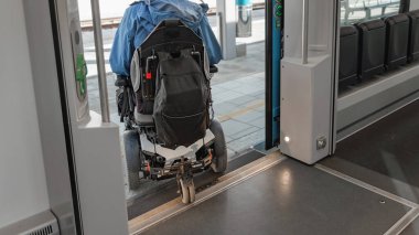 Elektrikli sandalyedeki engelli bir adam trenden çıkıyor. Erişilebilir seyahat ve kapsayıcı ulaşım kavramları.