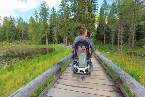 İtalya 'da yemyeşil yemliklerle çevrili Dolomitler' de tekerlekli sandalyeyle gezen biri ulaşılabilir patikalarda geziniyor. Huzurlu manzara doğada barışçıl bir deneyim sunuyor..