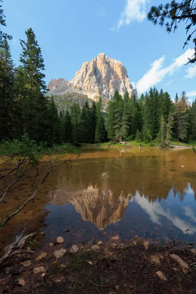 İtalya 'daki Dolomitlerin göz kamaştırıcı manzarası, verimli yeşilliklerle çevrili görkemli kayalık bir tepe ve açık bir günde güzel manzarayı yansıtan sakin bir gölet..