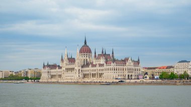 Tuna Nehri 'nin yanındaki Macar Parlamentosu binasının çarpıcı manzarası ikonik kulelerini ve mimari güzelliğini bulutlu gökyüzüne karşı sergiliyor..
