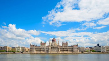 Macaristan Parlamentosu binaları Budapeşte 'deki Tuna Nehri boyunca bulutlarla dolu açık mavi bir gökyüzünün altında görkemli bir şekilde duruyor. Şehrin mimari güzelliğini gözler önüne seriyor..