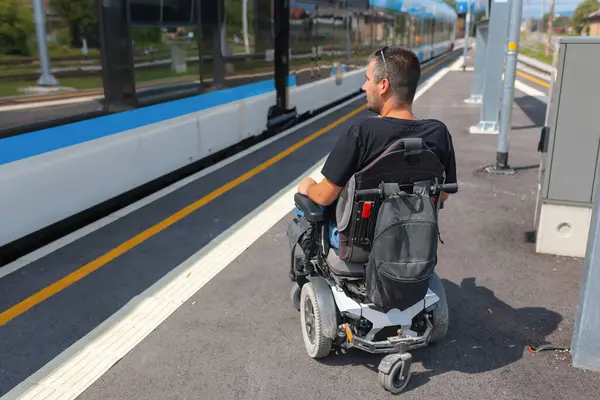 Erişilebilir tren yolculuğu kullanan tekerlekli sandalye kullanıcısı bir sonraki tren için bir istasyonda bekler. Bu deneyim tüm yolcular için kapsayıcı ulaşım seçeneklerinin önemini vurgular..