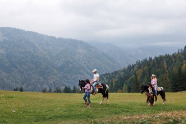 Batılı bir binicilik okulunun katılımcıları, sakin bir dağda, deneyimli eğitmenlerin rehberliği altında atlarıyla etkileşim halindedir.