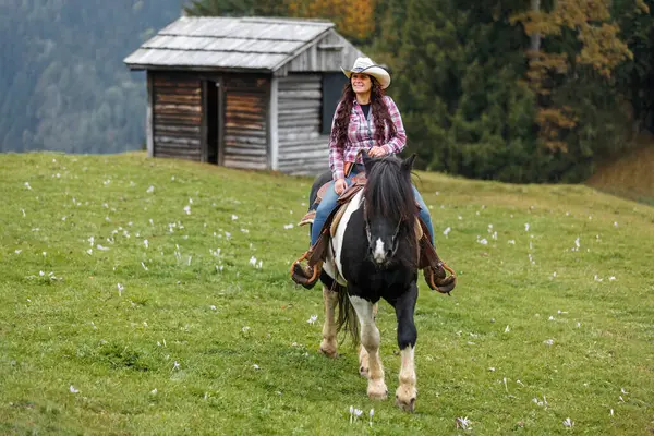 Kendine güvenen bir kovboy kızı sahnesinin özgün batı sahnesi. Hafif bir sis altında manzaralı dağ arazisinde at sürüyor.