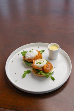 İki haşlanmış yumurta soslu yeşillik bir yatağa güzelce yerleştirilir, canlı ve iştah açıcı bir brunch tabağı oluşturur..