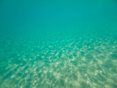 Deniz yatağı dokusu, mavi turkuaz ve beyaz kumlu deniz tabanı, su dalgaları yansıması, renk ve ışık oyunu, yukarıdan aşağı çekim. Yaz arkaplanı kavramı.
