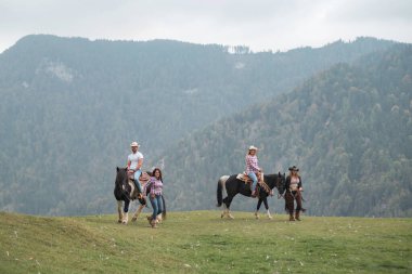 Batılı bir binicilik okulunun katılımcıları, sakin bir dağda, deneyimli eğitmenlerin rehberliği altında atlarıyla etkileşim halindedir.