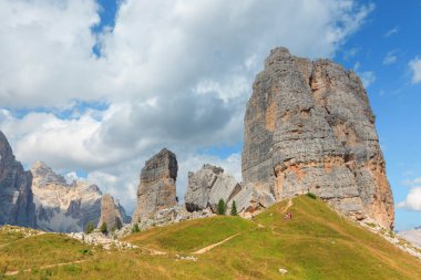 Yürüyüşçüler, İtalya 'daki Dolomitlerin çarpıcı manzarasının tadını çıkarıyorlar. Yükselen kaya oluşumları ve yemyeşil yeşil canlı mavi gökyüzünün altında nefes kesici bir zemin oluşturur..