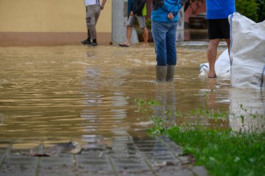 Sel suları kentsel alandaki caddeleri ve kaldırımları kaplarken, sakinler yükselen sularda yol alarak durumu kontrol altına almak için çalışıyorlar..