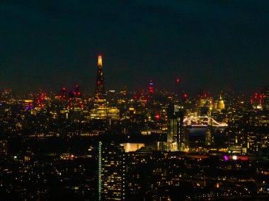 Parlak şehir ışıkları Thames nehrinden yansıyor. Londra 'da ikonik simgeler gece gökyüzüne karşı duruyor ve çarpıcı bir atmosfer yaratıyor..