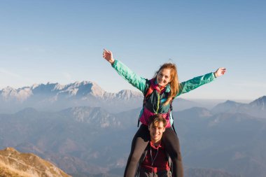 İki arkadaş, güneşli bir günde nefes kesici manzaralar ve temiz havanın tadını çıkarırken dağın zirvesine ulaşmayı kutluyorlar..